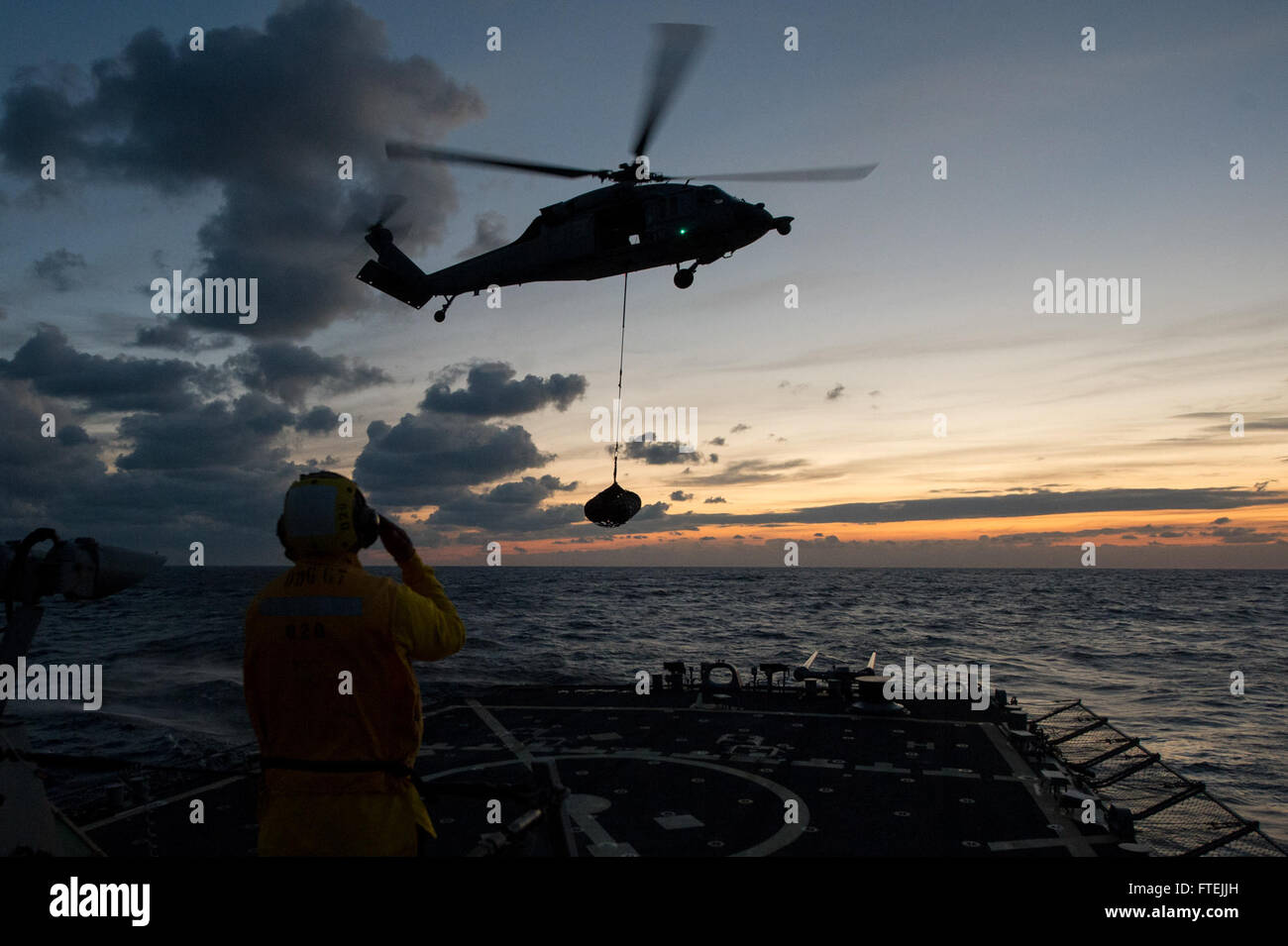 MEDITERRANEAN SEA (Dec. 11, 2014) Boatswain’s Mate 3rd Class Dontrell Dorsett, from Fort Worth, Texas, directs An MH 60S Sea Hawk helicopter attached to the Dragon Whales of Helicopter Sea Combat Squadron (HSC) 28 to approach USS Cole (DDG 67) during deck-landing qualifications, Dec. 11 2014. Cole, an Arleigh Burke-class guided-missile destroyer, homeported in Norfolk, is conducting naval operations in the U.S. 6th Fleet area of operations in support of U.S. national security interests in Europe. Stock Photo