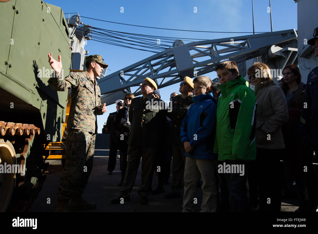 VALENCIA, Spain (Dec. 31, 2014) Damian Cantu, a heavy equipment operator with Combat Logistics Battalion 24, 24th Marine Expeditionary Unit, explains the capabilities of an M9 Armored Combat Earthmover to Spanish civilians and government and military officials aboard the USS Fort McHenry (LSD 43) in Valencia, Spain, Dec. 31, 2014. The 24th MEU and Iwo Jima Amphibious Ready Group are conducting naval operations in the U.S. 6th Fleet area of operations in support of U.S. national security interests in Europe. Stock Photo