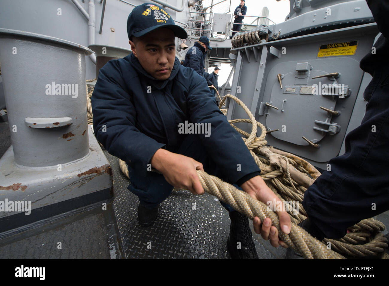 CIVITAVECCHIA, Italy (Jan. 3, 2015) Seaman Paul Banez, originally from Anchorage, Alaska, heaves a mooring line as amphibious assault ship USS Iwo Jima (LHD 7) departs Civitavecchia, Italy, Jan. 3, 2015. Iwo Jima pulled in to Civitavecchia Dec. 30 for a scheduled port visit before continuing its deployment in support of maritime security operations and theater security cooperation efforts in the U.S. 6th Fleet areas of operations. Stock Photo