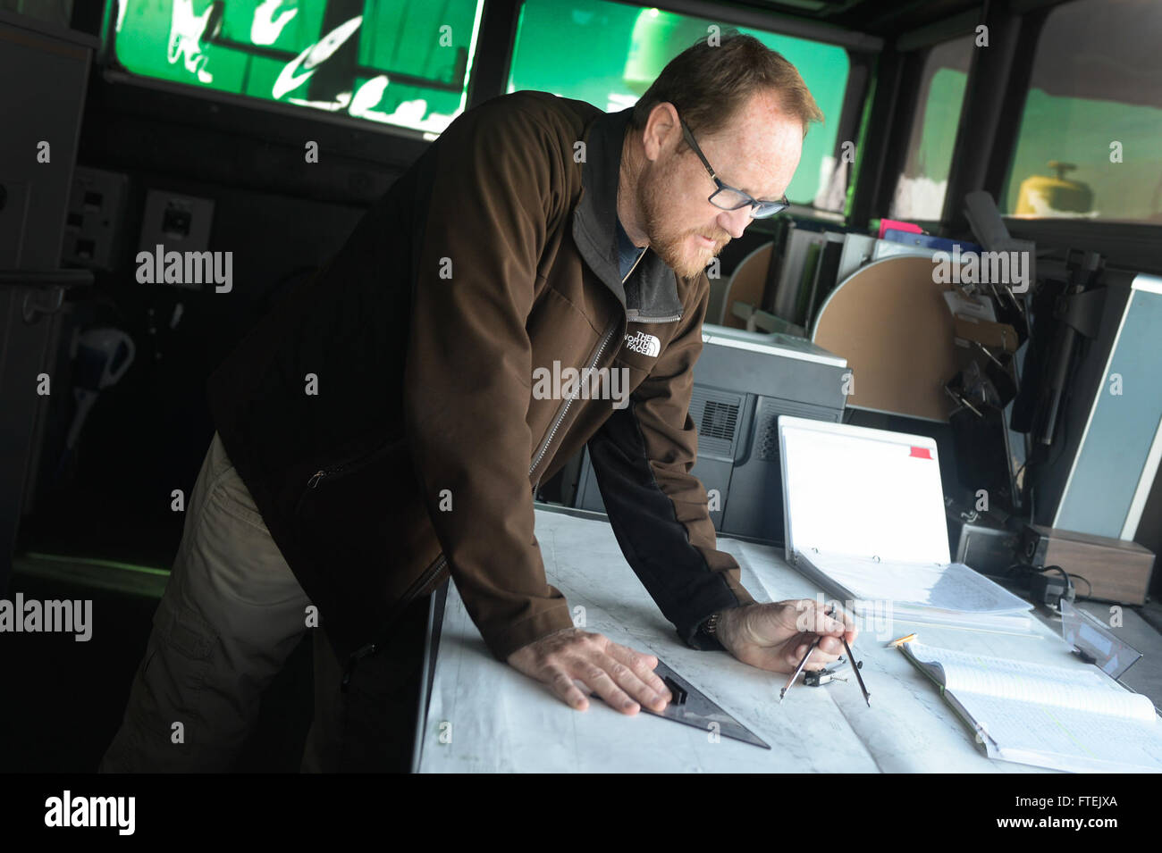 ATLANTIC OCEAN (Jan. 3, 2015) Ray Barnett, USNS Spearhead (JHSV 1) second officer , checks the ship's course of sail against nautical charts in heavy seas Jan. 3, 2015. Spearhead is on a scheduled deployment to the U.S. 6th Fleet area of operations to support the international collaborative capacity-building program Africa Partnership Station. Stock Photo