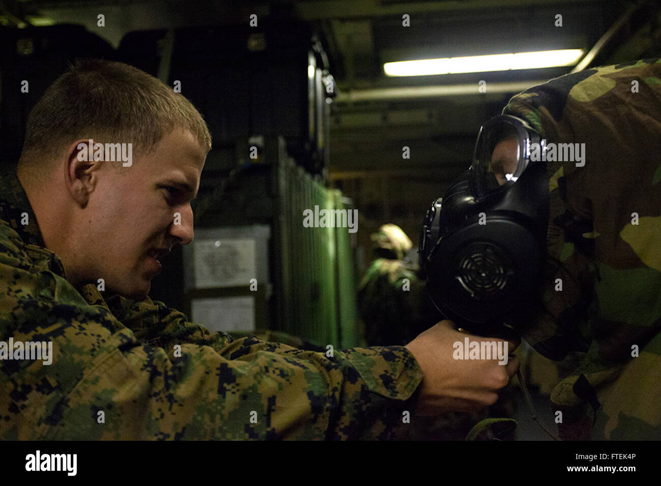 150108-M-QZ288-130 MEDITERRANEAN SEA (Jan. 8, 2015) Cpl. Evan A. Lafoose, a chemical, biological, radiological, and nuclear defense specialist with the 24th Marine Expeditionary Unit’s Command Element, adjusts a student’s M50 joint-service general-purpose gas mask during a mission-oriented protective posture gear refresher course aboard USS Iwo Jima (LHD 7) Jan. 8, 2015. The 24th MEU and Iwo Jima Amphibious Ready Group are conducting naval operations in the U.S. 6th Fleet area of operations in support of U.S. national security interests in Europe. (U.S. Marine Corps photo by Lance Cpl. Austin  Stock Photo