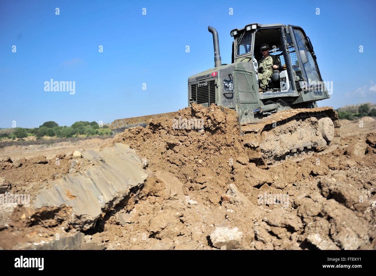 NAVAL STATION ROTA, Spain (Feb. 13, 2015) Equipment Operator 3rd Class David Mortensen, assigned to Naval Mobile Construction Battalion (NMCB) 11, operates a bulldozer to level the area where a Helicopter Landing Zone (HLZ) will be placed Feb. 13, 2015. The HLZ project, once finished, will assist in the bilateral training with the Spanish military, Explosive Ordnance Disposal and will not interfere with the main airstrip of Naval Station Rota. (U.S. Navy photo by Mass Communication Specialist 1st Class Michael C. Barton/Released) Stock Photo
