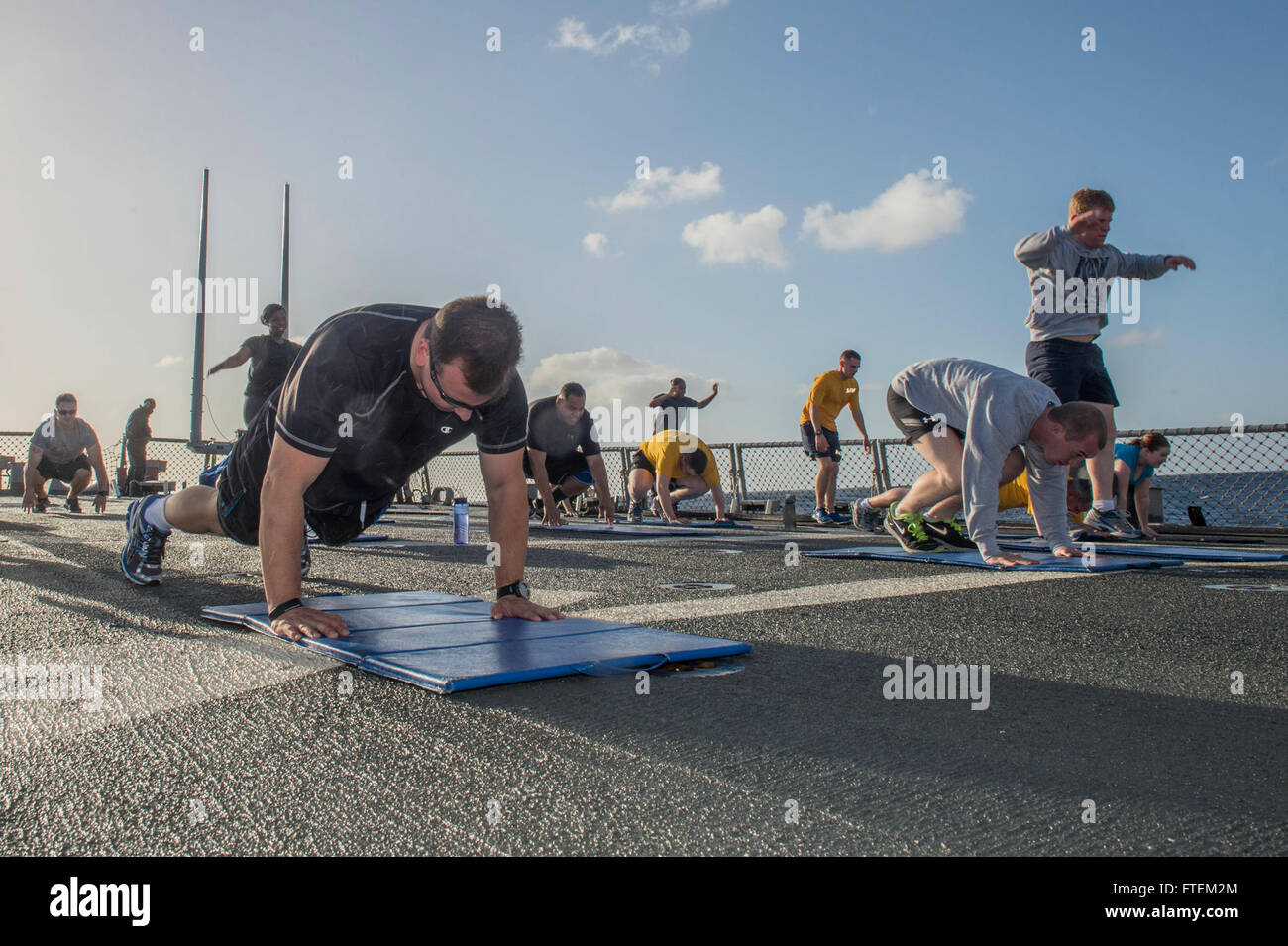 ATLANTIC OCEAN (Feb. 19, 2015) Sailors aboard USS Laboon (DDG 58) perform “burpees” during command physical training on the flight deck Feb. 19, 2015.  Laboon, an Arleigh Burke-class guided-missile destroyer home ported in Norfolk, is underway conducting naval operations in the U.S. 6th Fleet area of operations in support of U.S. national security interests in Europe. Stock Photo