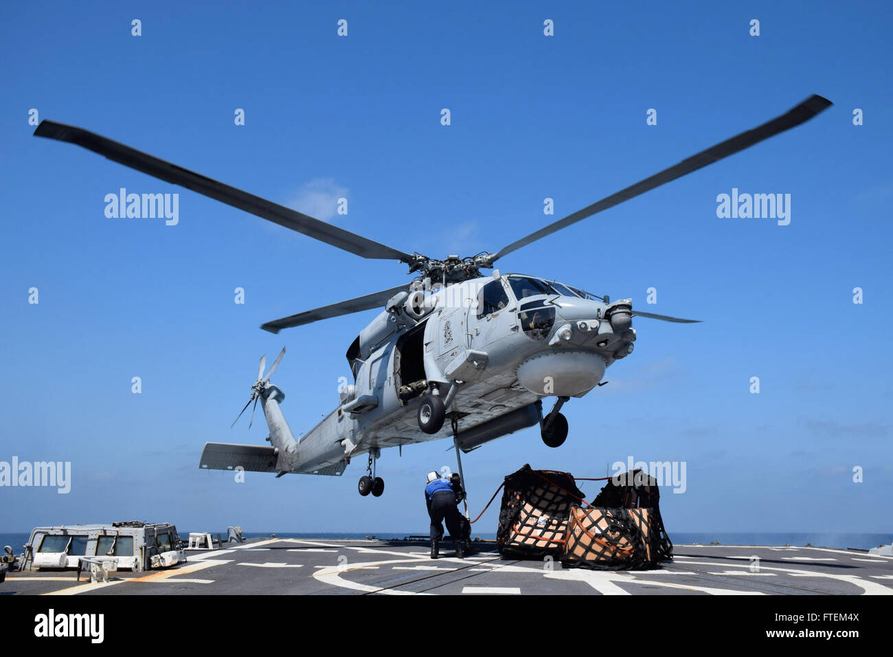 HORN OF AFRICA (Feb. 23, 2015) Flight deck crew members aboard USS Oscar Austin (DDG 79) attach supplies to an SH-60F Seahawk during a vertical replenishment with the Royal Australian navy ship HMAS Success (OR 304)Feb. 23, 2015. Oscar Austin, an Arleigh Burke-class guided-missile destroyer, homeported in Norfolk, is conducting naval operations in the U.S. 6th Fleet area of operations in support of U.S. national security interests in Europe and Africa. Stock Photo