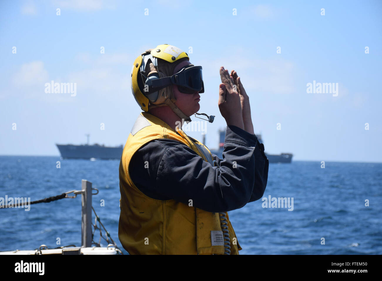 HORN OF AFRICA (Feb. 23, 2015) Boatswain’s Mate Seaman Michael Hungelmann signals an SH-60F Seahawk during a vertical replenishment with the Royal Australian navy ship HMAS Success (OR 304) Feb. 23, 2015. Oscar Austin, an Arleigh Burke-class guided-missile destroyer, homeported in Norfolk, is conducting naval operations in the U.S. 6th Fleet area of operations in support of U.S. national security interests in Europe and Africa. Stock Photo
