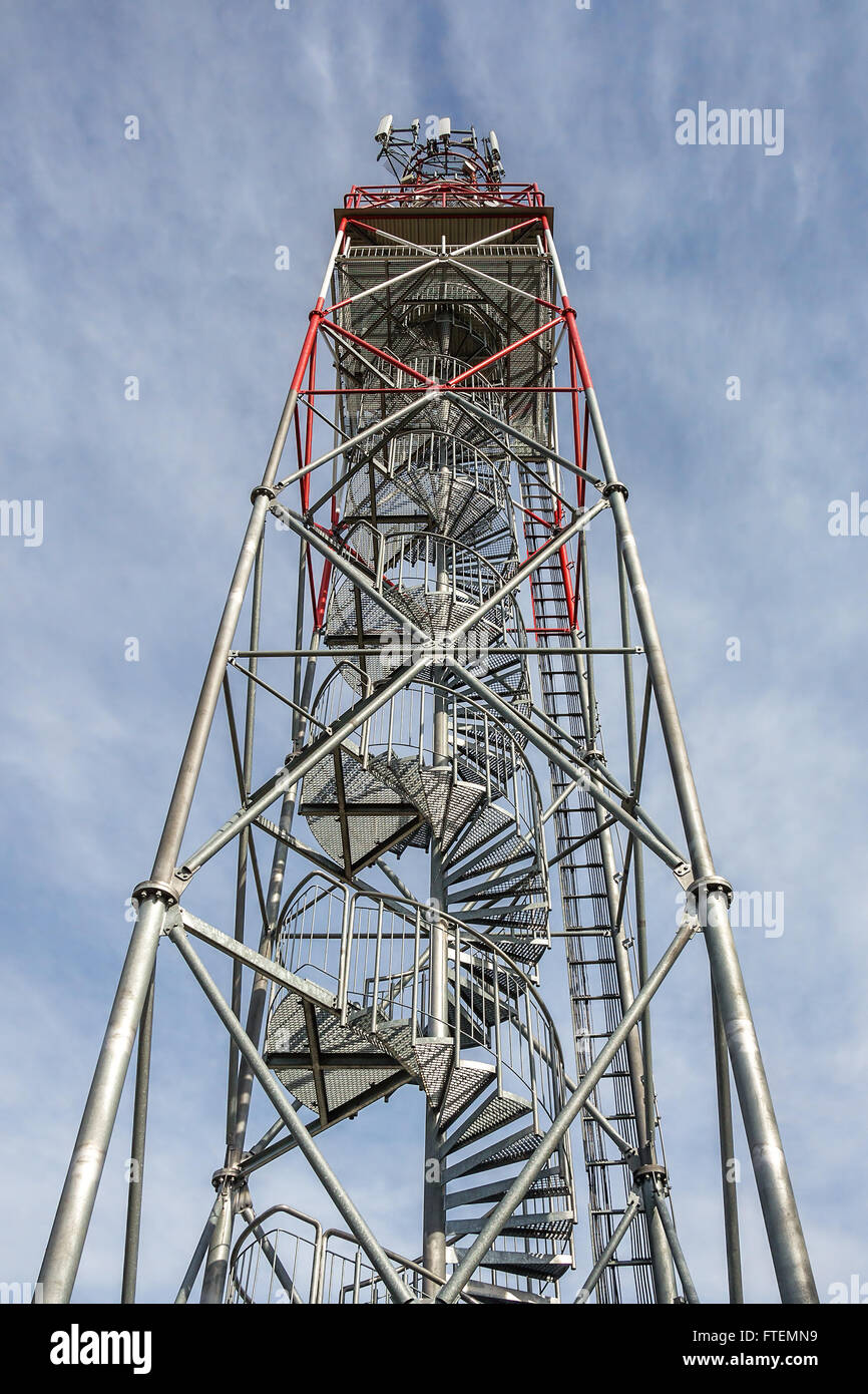Tall steel lookout tower with spiral stairs, upright against blue sky Stock Photo