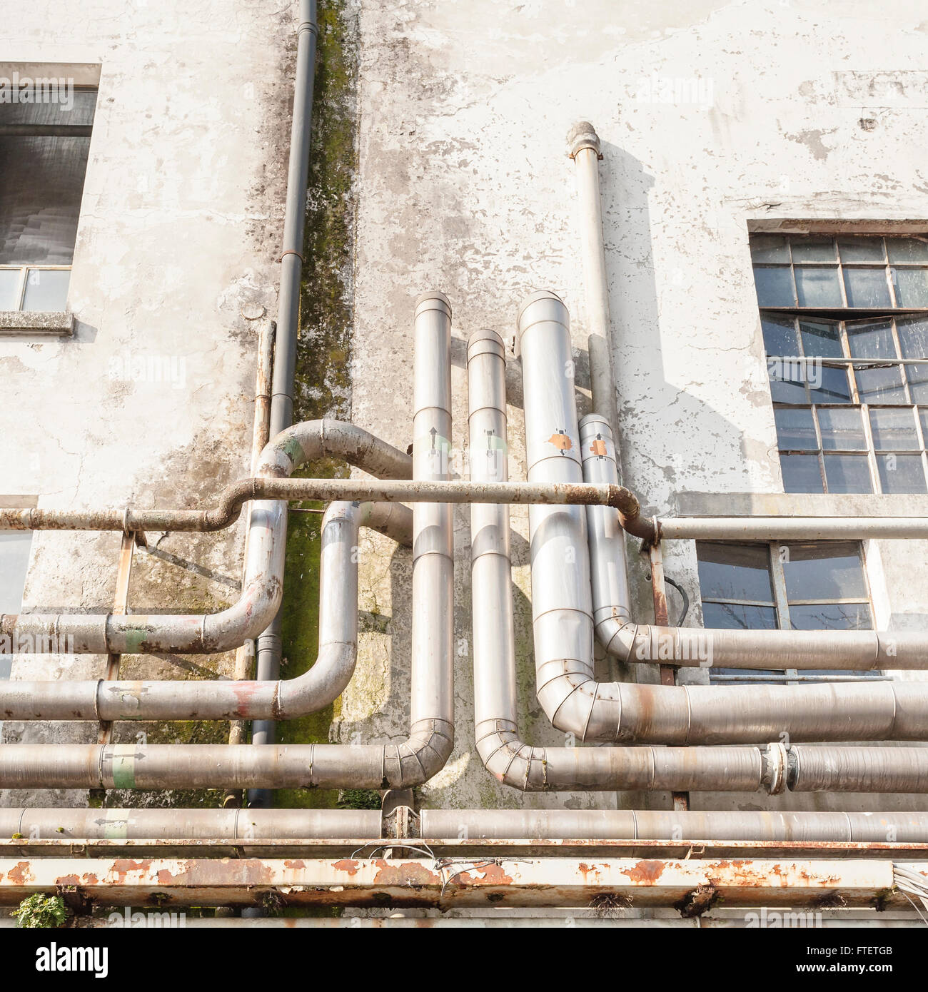 Old pipes on the wall outside of an old abandoned factory. Stock Photo