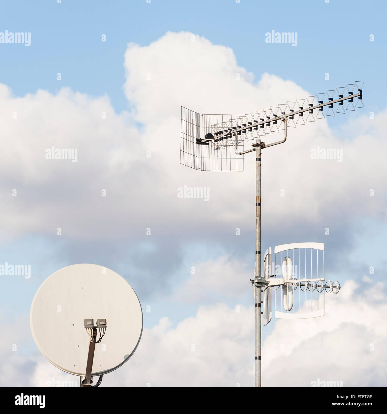 TV aerial and satellite dish against a blue sky Stock Photo