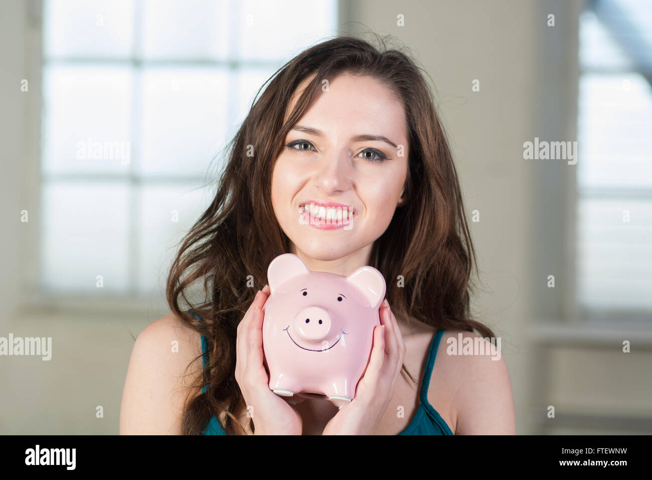 Happy young woman holding a piggy bank Stock Photo - Alamy