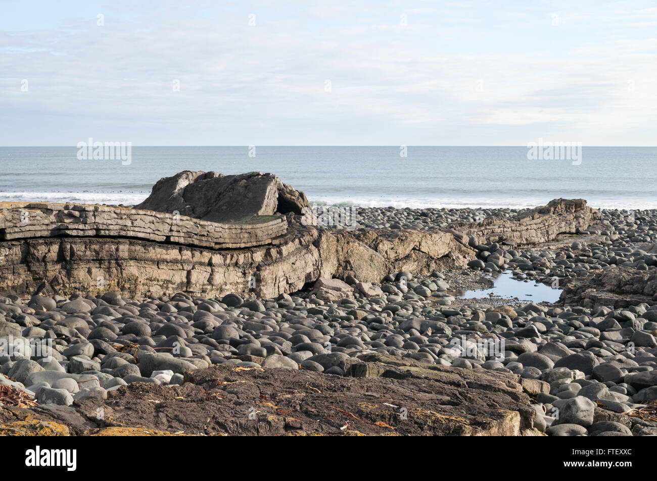 Greymare Rock crossing the beach at Dunstanburgh, Northumberland, England, UK Stock Photo