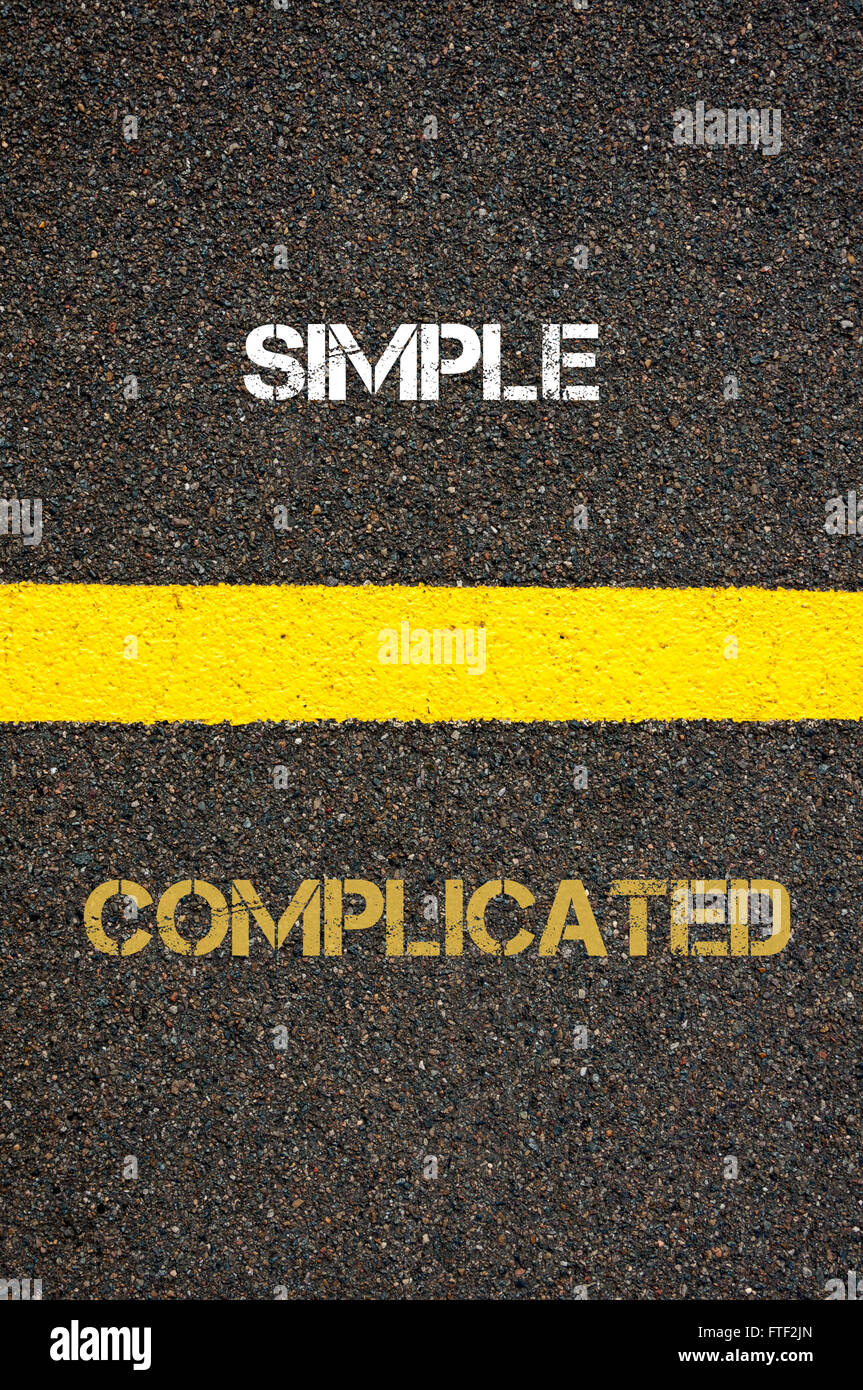 Antonym decision concept of COMPLICATED versus SIMPLE written over tarmac, road marking yellow paint separating line between words Stock Photo