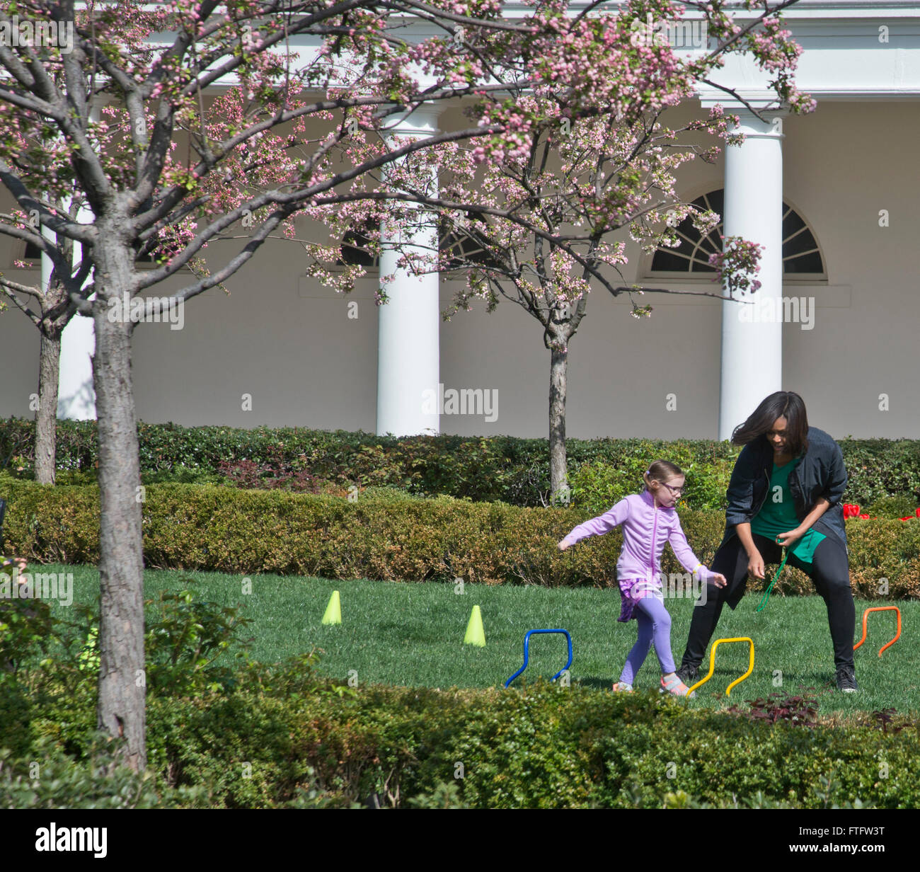 Washington DC, USA. 28th March, 2016.First Lady Michelle Obama encourages a participant in an running course in the Rose Garden during the annual White House Easter Egg roll .President Barack Obama and the First Lady were joined by thousands of people on the South Lawn of the White House. Credit:  Patsy Lynch/Alamy Live News Stock Photo