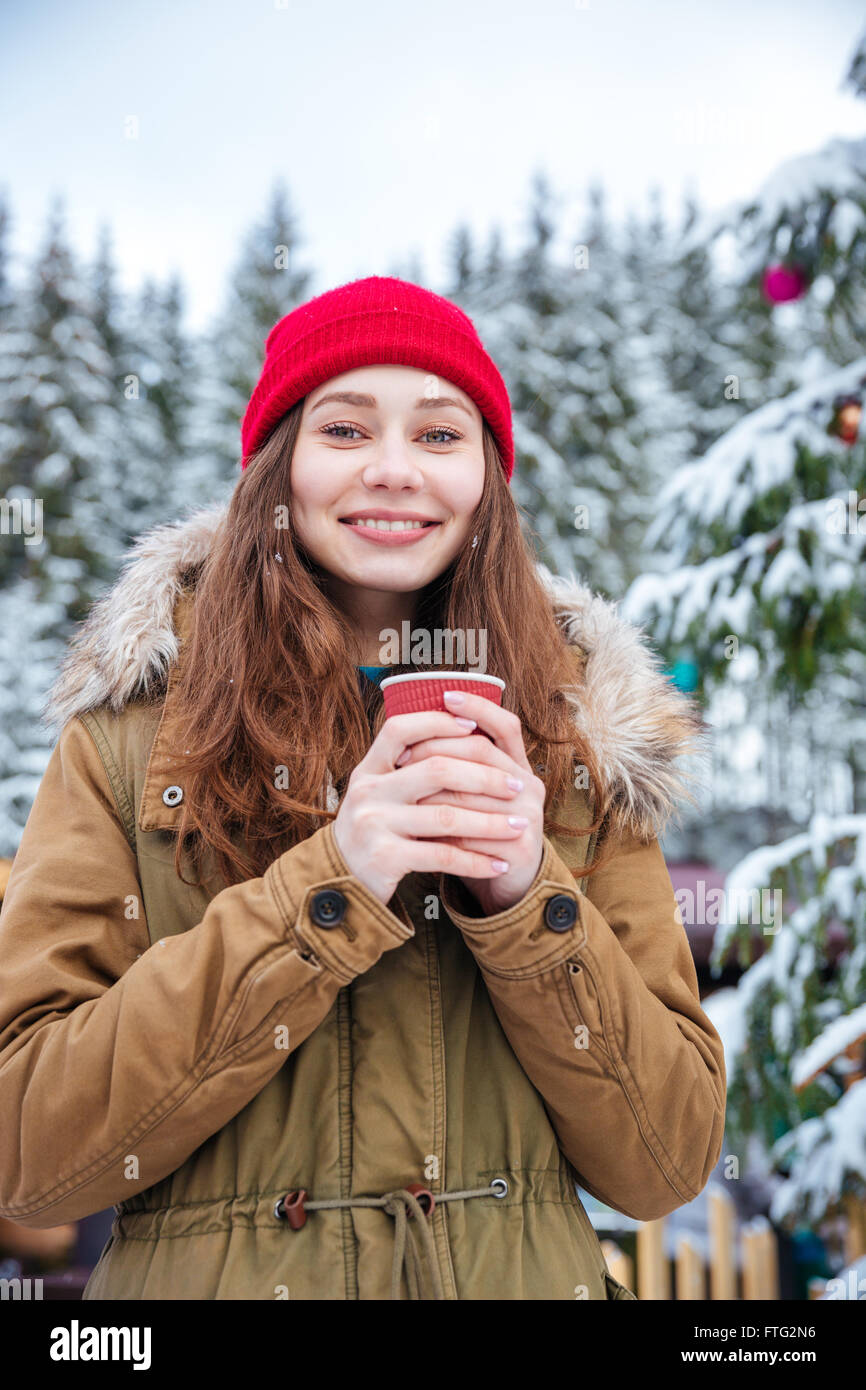 Portrait of cheerful attractive young woman drinking hot coffee near ...