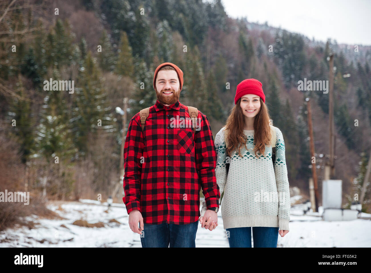 Smiling young couple traveling in winter forest Stock Photo