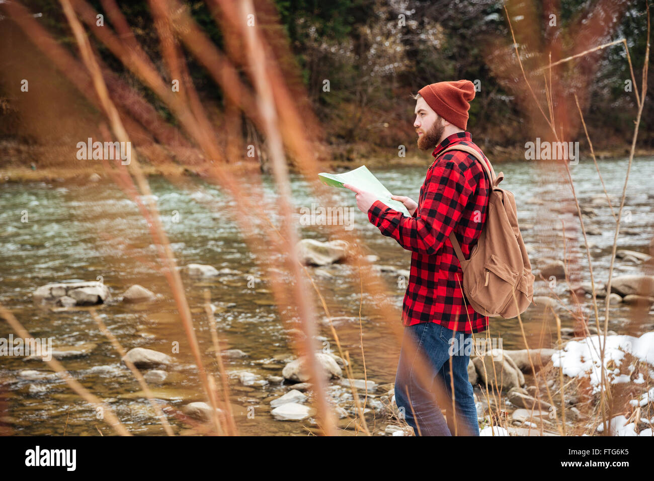 Male hiker standing on the river and holding map Stock Photo - Alamy