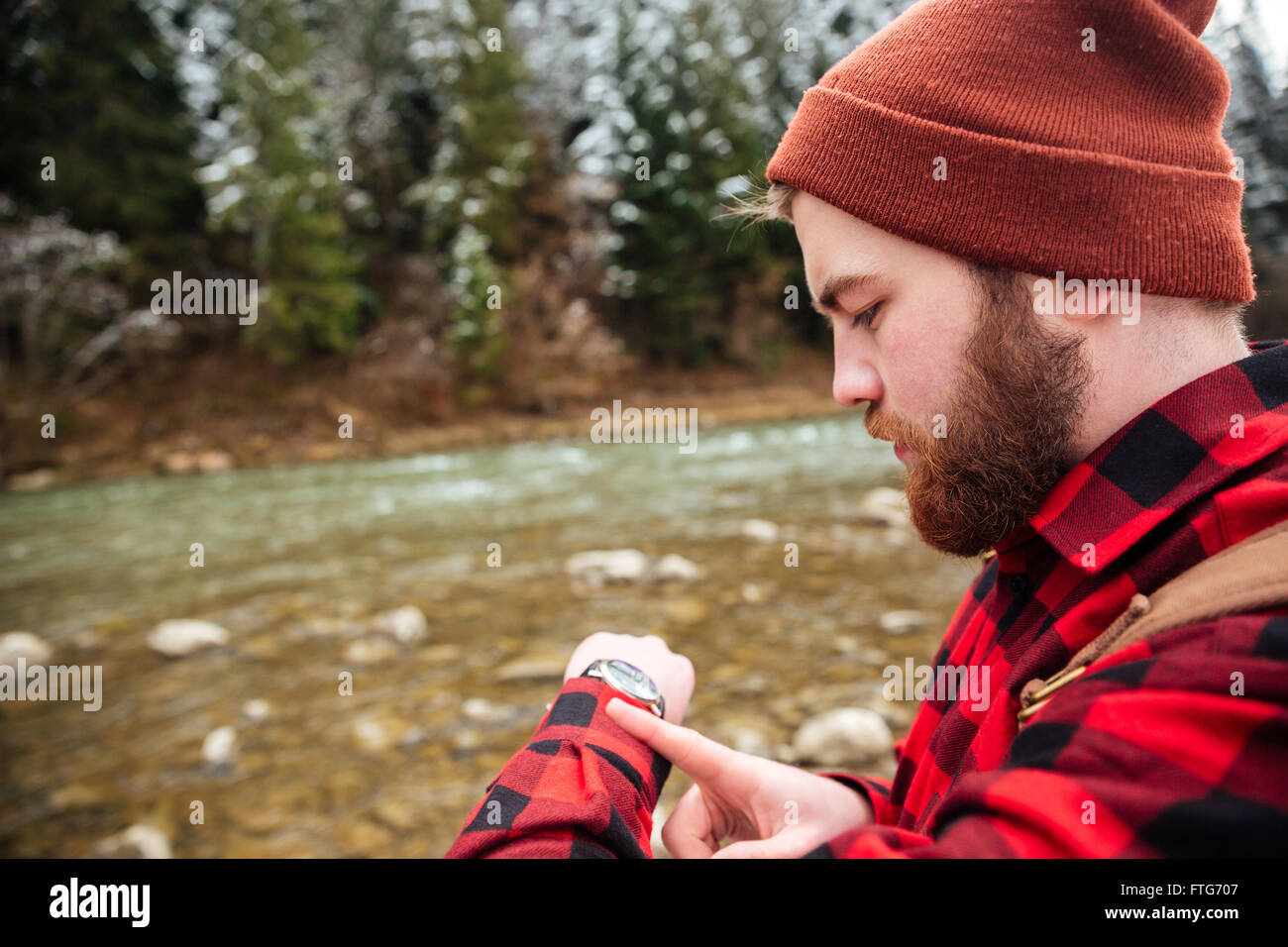 Man looking on the wrist watch outdoors with river on background Stock Photo