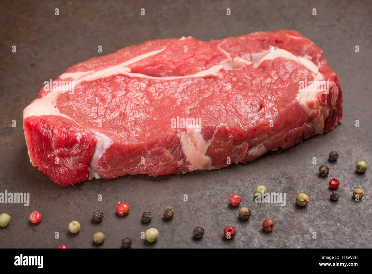 Raw dry aged rib eye steak with peppercorns Stock Photo