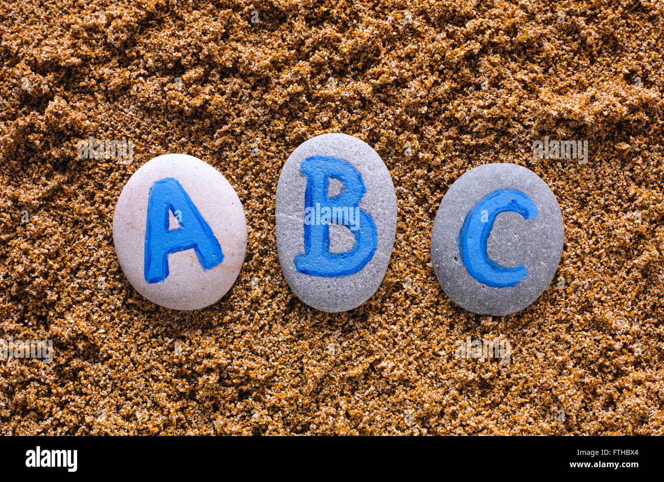 ABC letters drawn on stones spell out on sea sand. Letters drawn by me ...