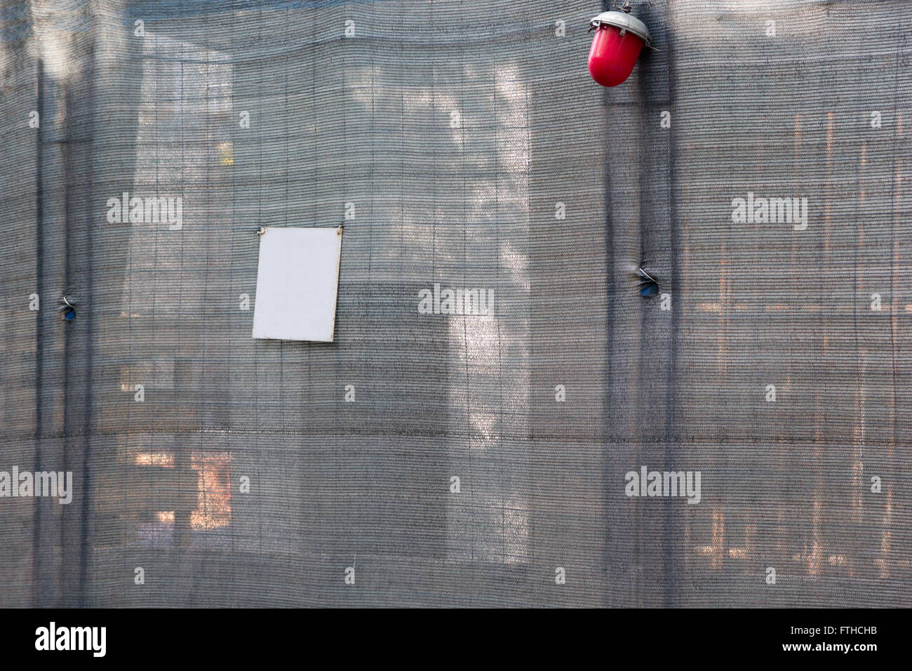 gray mesh fence with red lantern on a building site Stock Photo