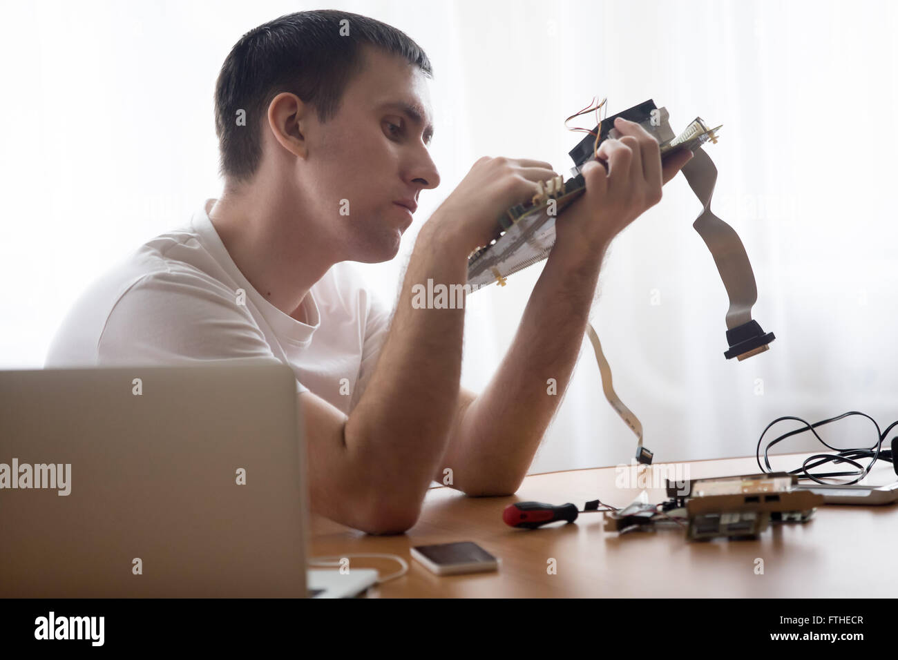 Portrait of computer young engineer working with broken pc parts sitting in the small home office Stock Photo