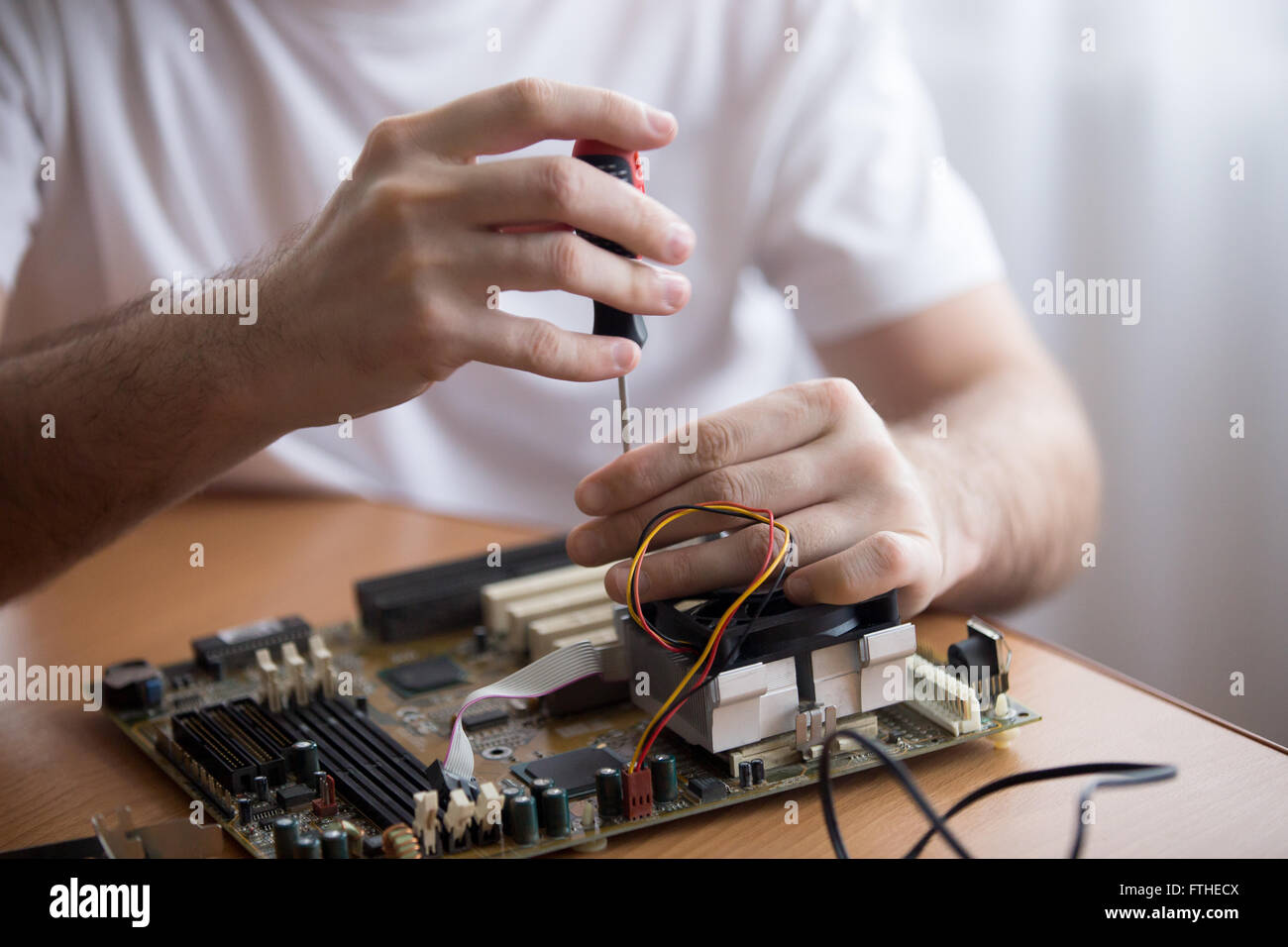 Close-up of hands of young computer engineer fixing broken pc parts at the desk in the home office Stock Photo