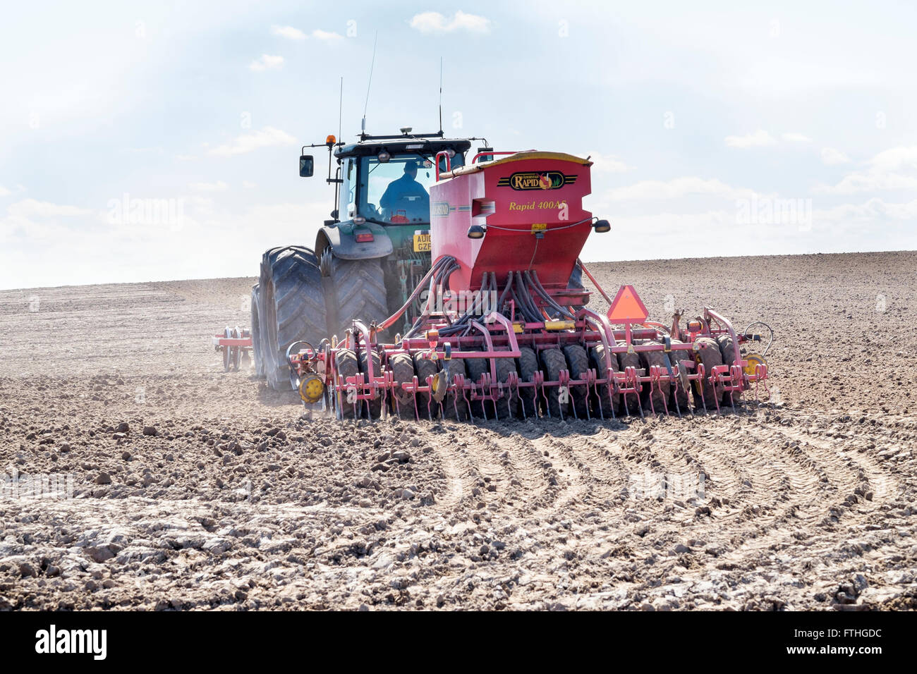 Tractor sowing seeds in a prepared field via a Vaderstad Rapid 400 AS drill. Stock Photo