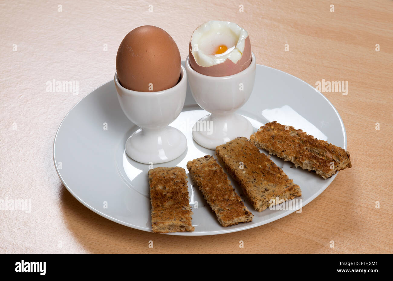 Breakfast of boiled eggs and toast soldiers on a white plate Stock