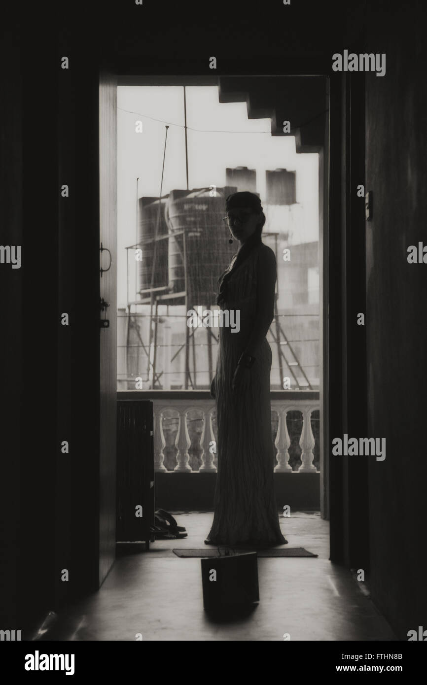 Silhouette of a young woman wearing a long dress in a doorway Stock Photo