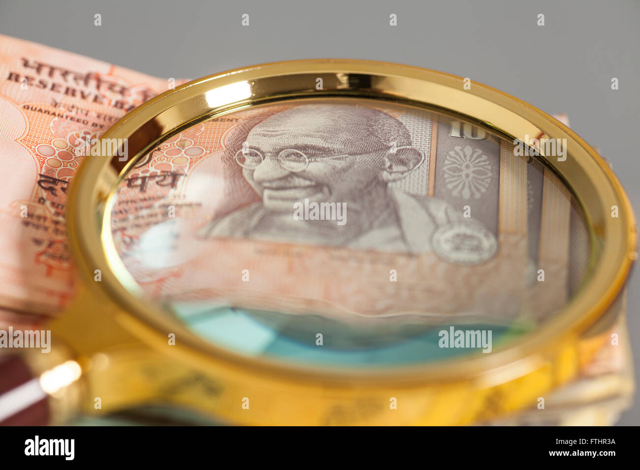 Indian Currency Rupee Notes with magnifying glass on gray Stock Photo ...
