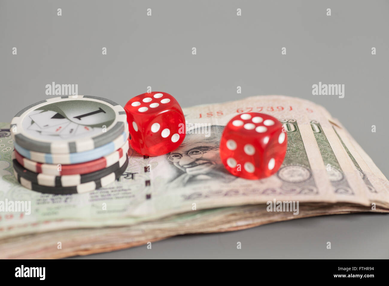 Poker chips and red dice on Indian Currency Rupee bank notes isolated