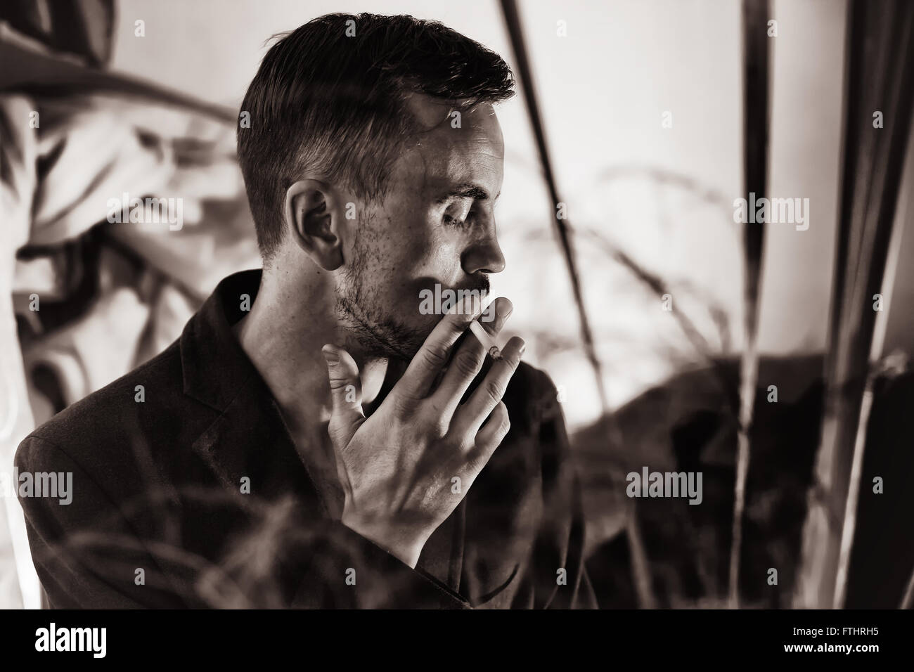 Portrait of a young handsome man dressed in a jacket with cigarette Stock Photo