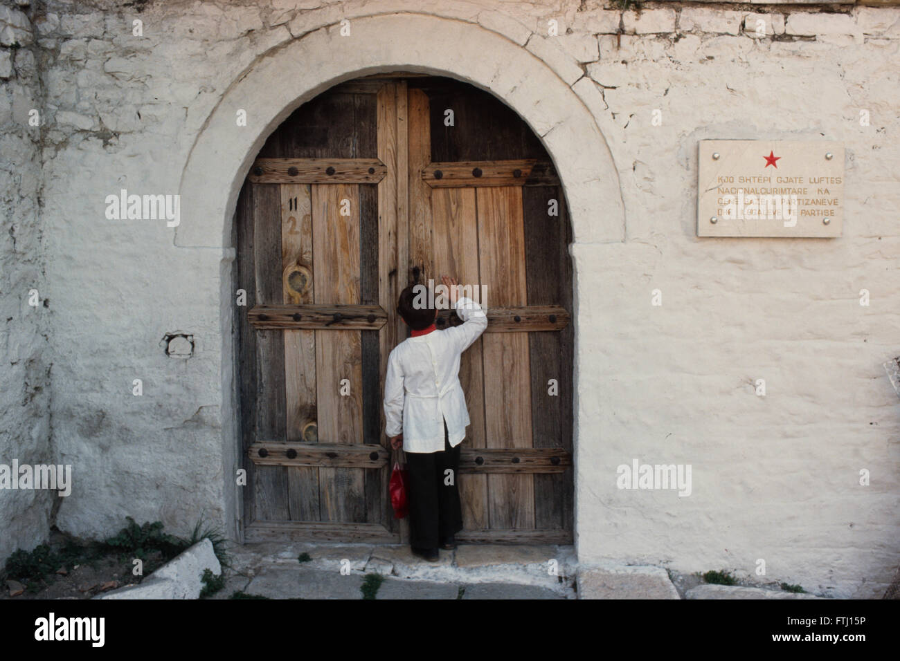 A boy knock on a wooden door of a house that was used by partisans during WW2. Stock Photo