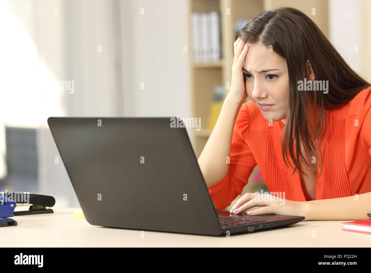 Sad and worried entrepreneur working on line with a laptop in an office desk or home Stock Photo