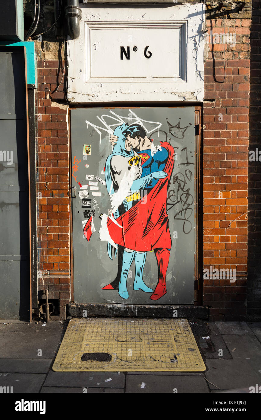 Superman Kissing Batman graffiti on a doorway in London's Soho, UK Stock Photo