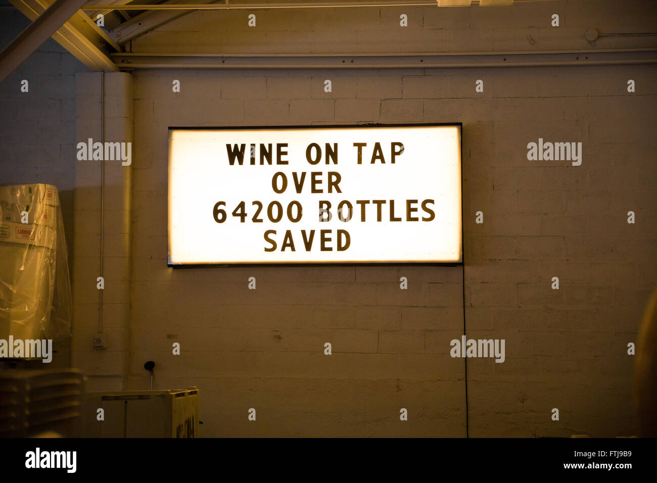 Winery that sells growler fills of wine has a sign that says wine on tap over 64200 bottles saved. Stock Photo