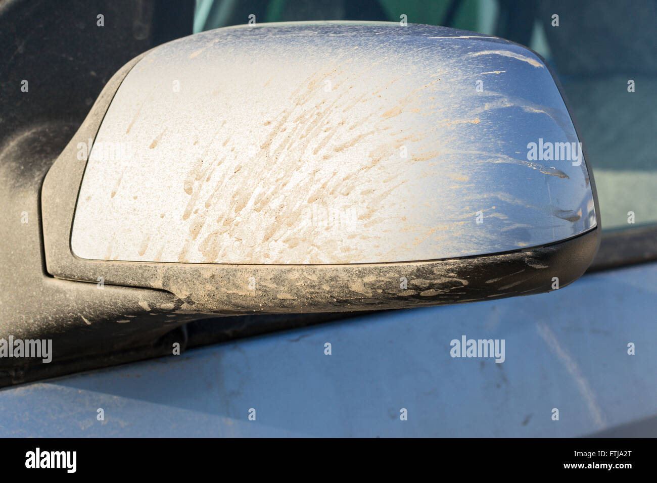 Mud stained car wing mirror in blue metallic paint with dry mud stains and streaks. Stock Photo