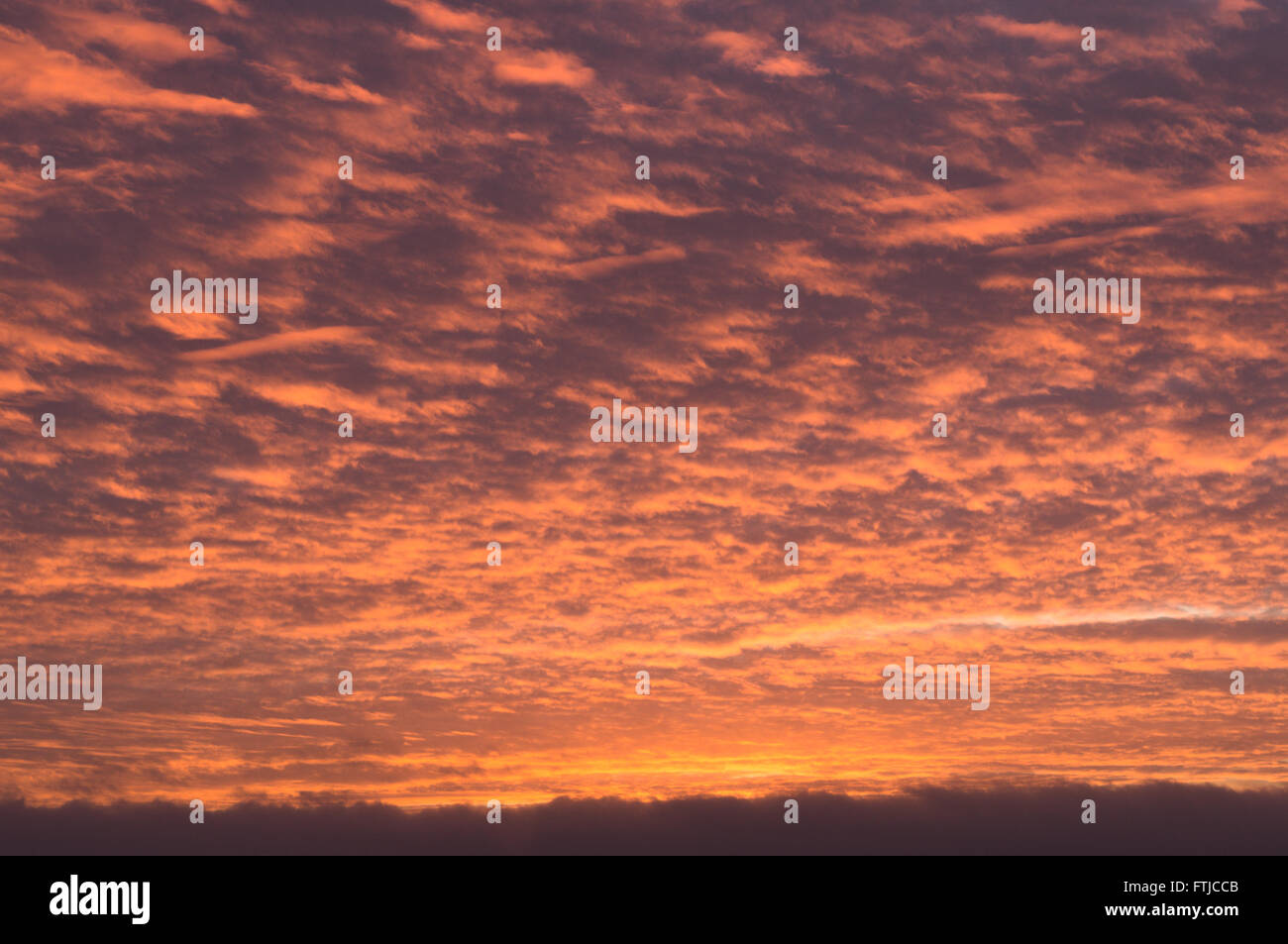 Sunset sky covered by fiery orange clouds Stock Photo