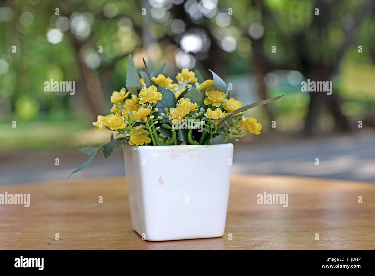 yellow artificial flower in flowerpot on the table Stock Photo