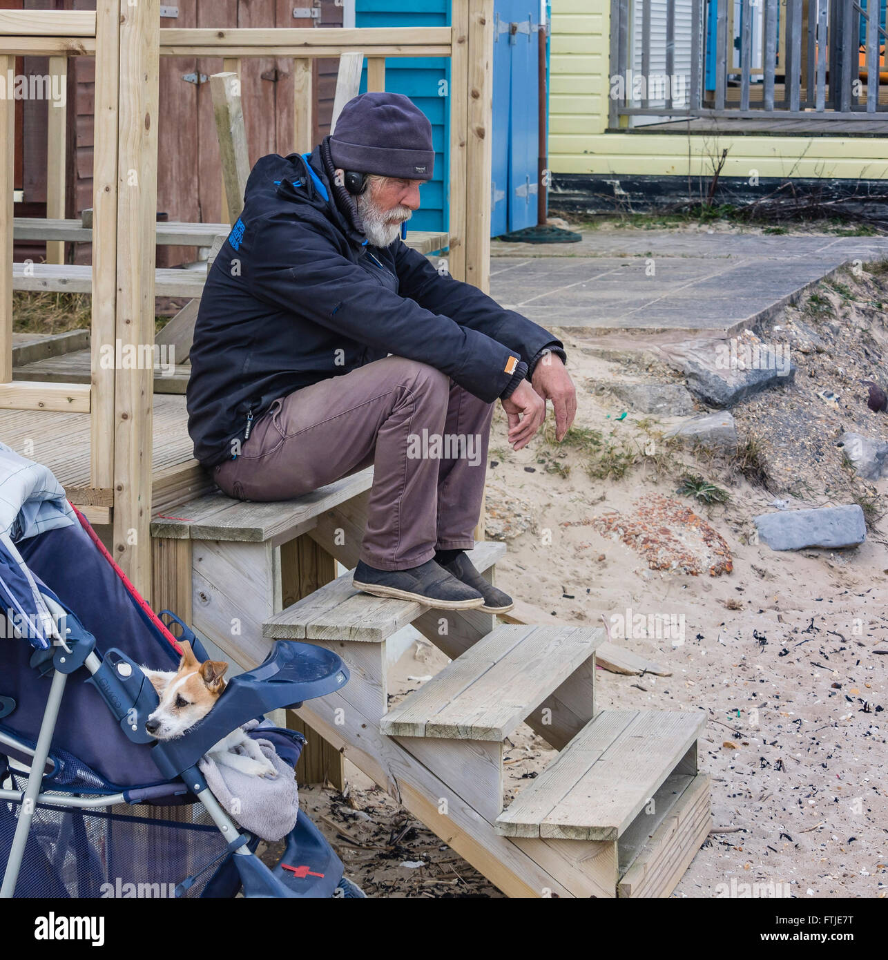 A mature man sitting on steps in a thoughtful mode with his dog, Jack Russell Terrier, alongside. Stock Photo