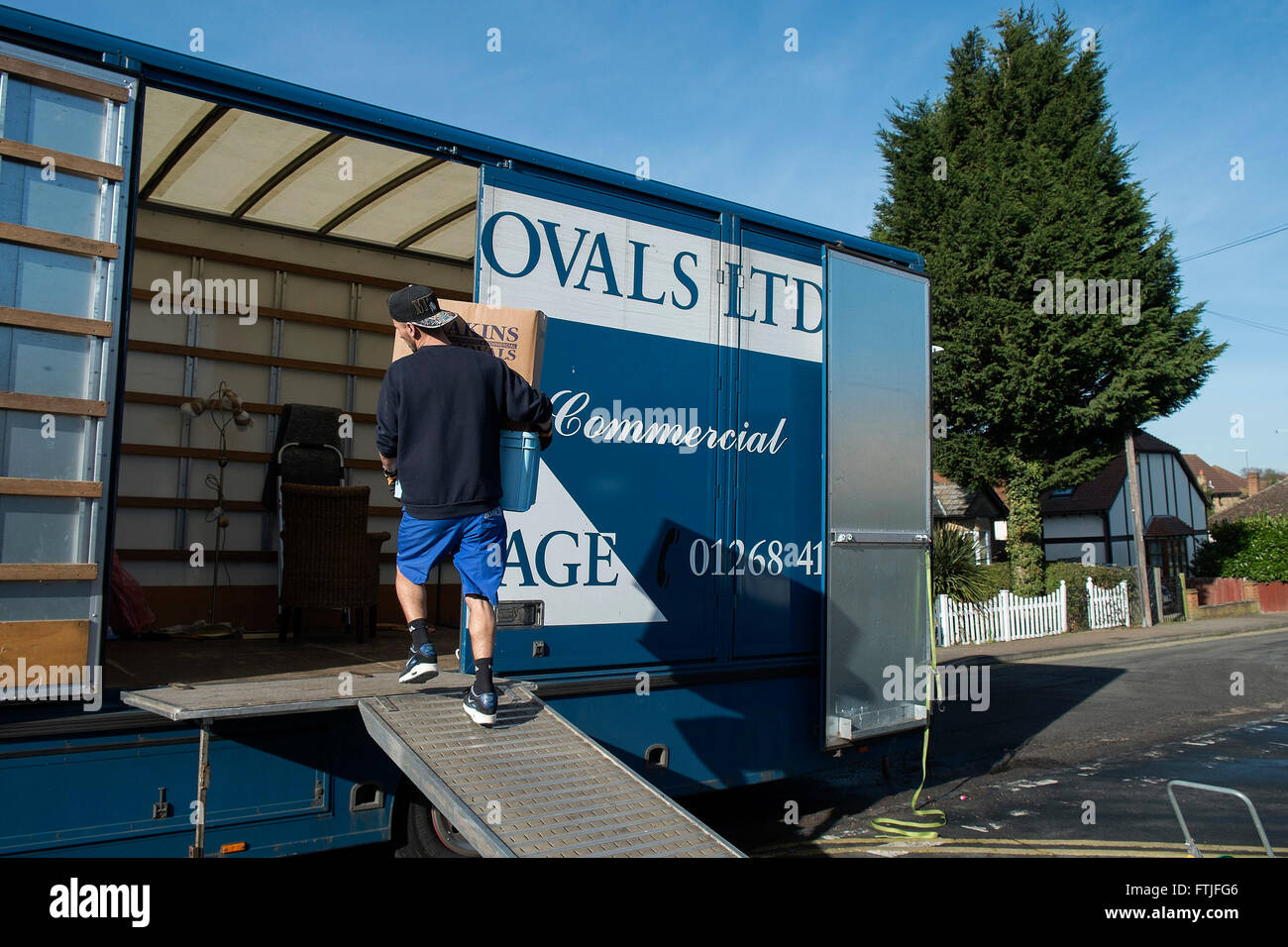 A removal man loading household items into a removal van. Stock Photo