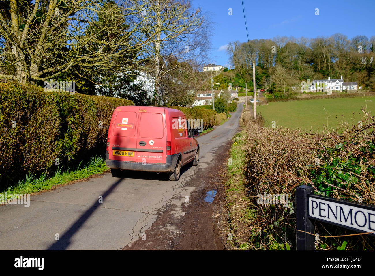 Red Royal Mail post van in country lane delivering post/mail in rural area, in early spring Gloucestershire England UK Stock Photo