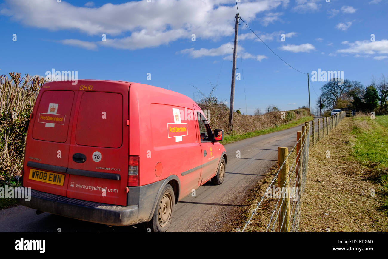 Red Royal Mail post van in country lane delivering post/mail in rural area, in early spring Gloucestershire England UK Stock Photo
