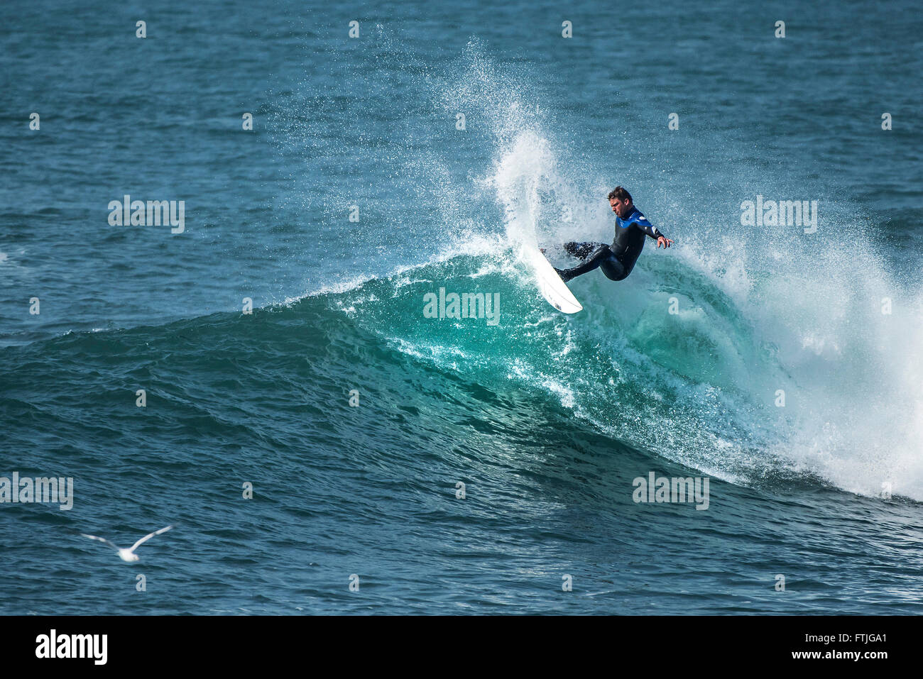 A surfer in spectacular action riding a wave at Porthleven in Cornwall, England. Stock Photo