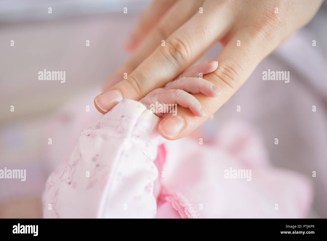 mother's finger holding babies hand Stock Photo