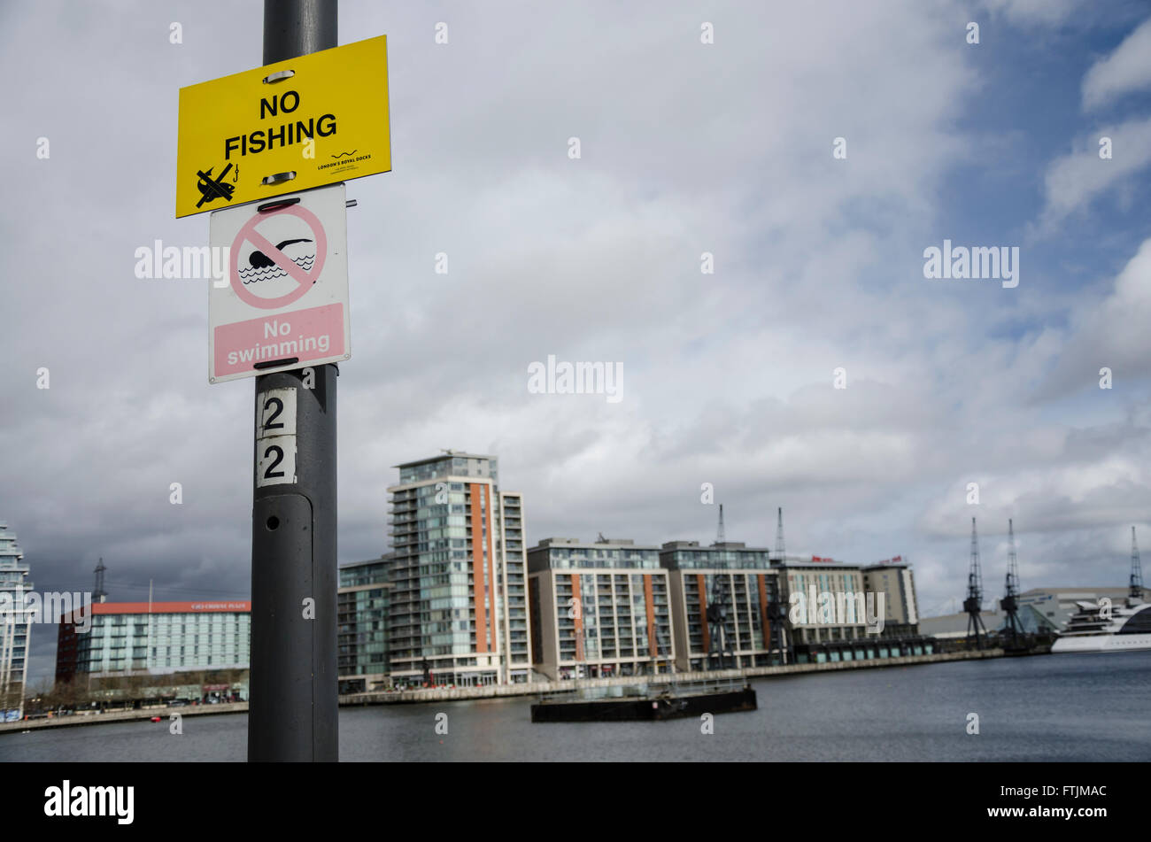 Signs on a lamppost at The Royal Victoria Dock stating that fishing and swimming are not allowed. Stock Photo