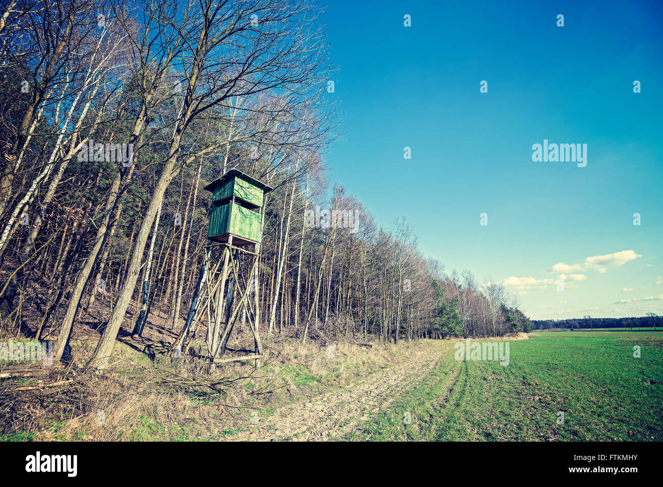 Vintage cross processed photo of hunting pulpit at the edge of a forest in spring, Poland. Stock Photo