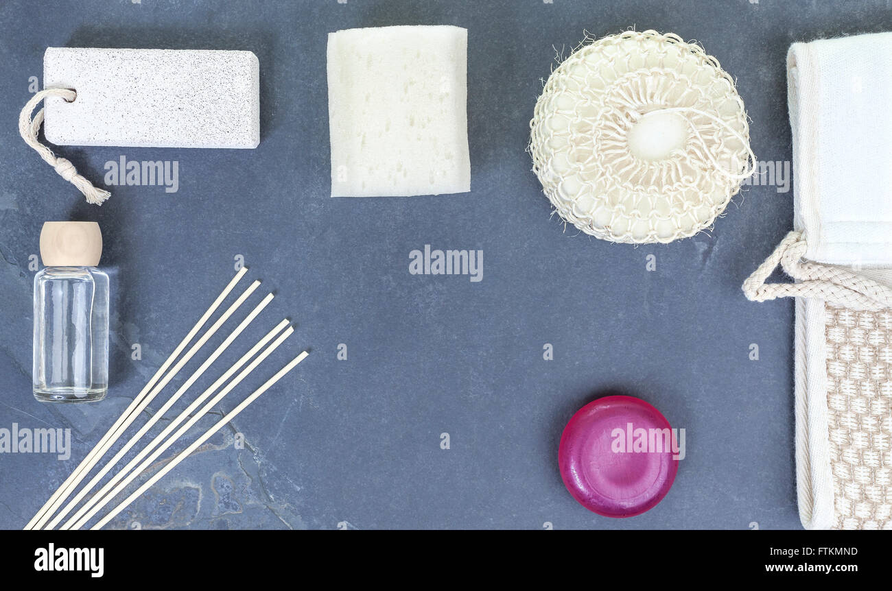 Spa flat lay background with sponge, facecloth, aroma sticks, oil; soap, pumice over natural cracked slate. Stock Photo