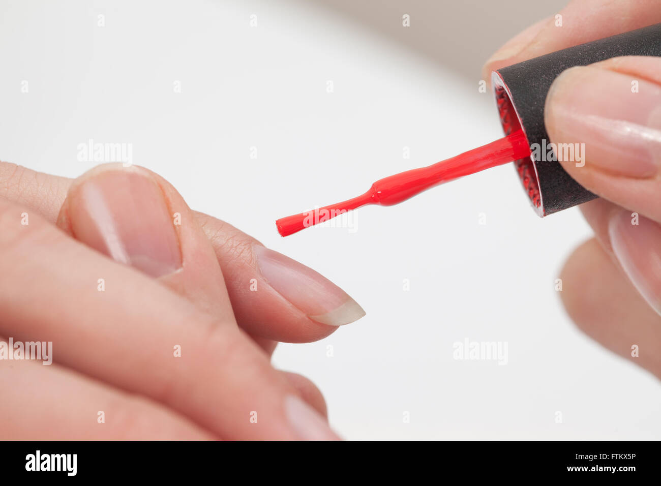 Manicure specialist painting clients nails red at the nail salon Stock