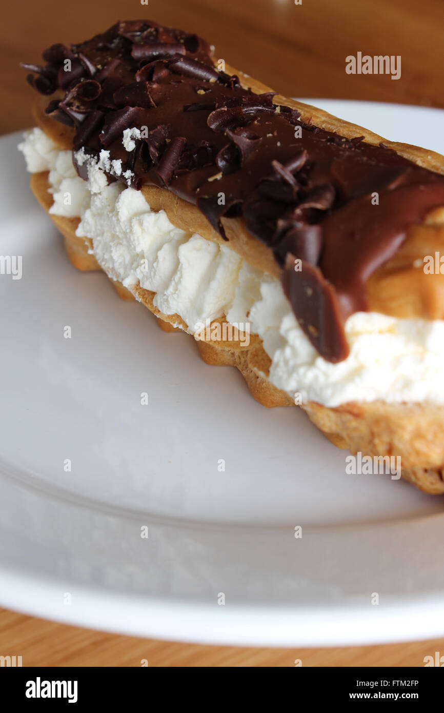 A chocolate Eclair served on a plate ready to eat Stock Photo