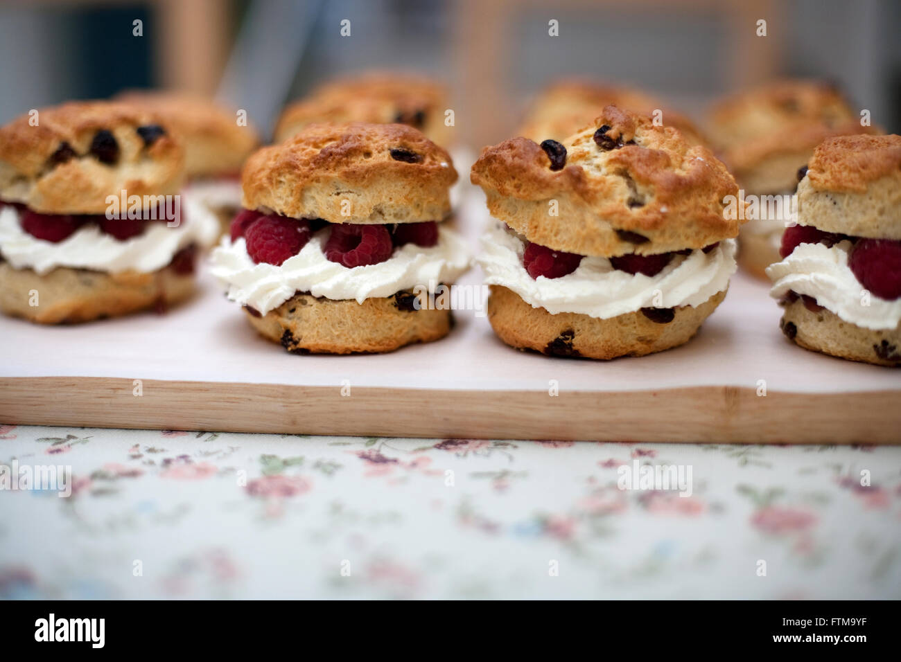 Fruit scones with cream and raspberry filling on a wooden board on a